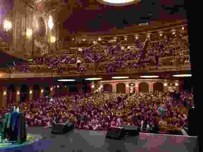 A Packed Audience Filling The Paramount Center, Their Faces Illuminated By The Glow Of The Stage. Christmas At Emerson S: A Tiny Romance With A Big Heart